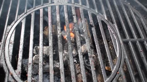 outdoor grill bars closeup showing flames and smoke from burning charcoal