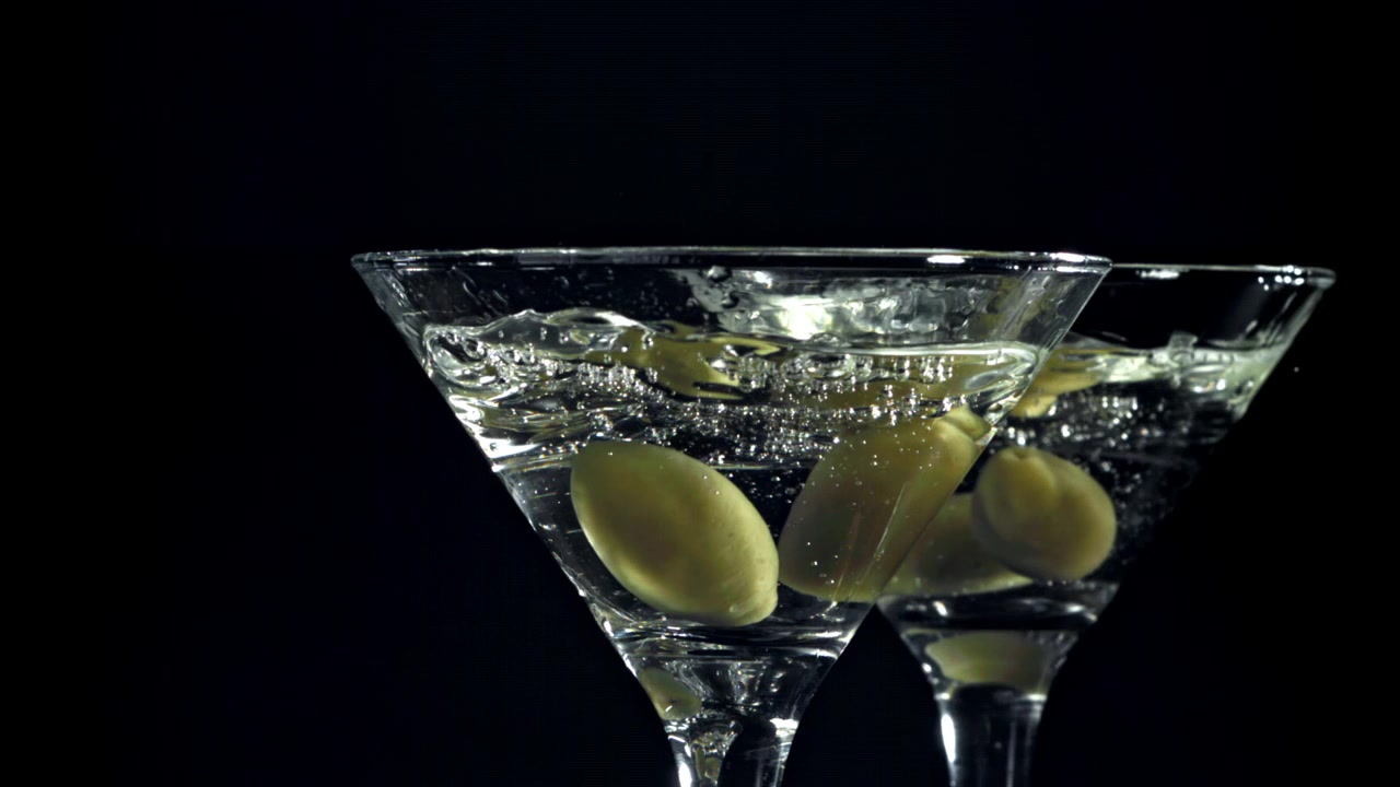 Bicchieri da Martini con olive e bollicine su sfondo nero