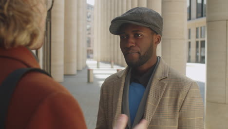 elegante hombre de negocios afroamericano hablando con un colega al aire libre