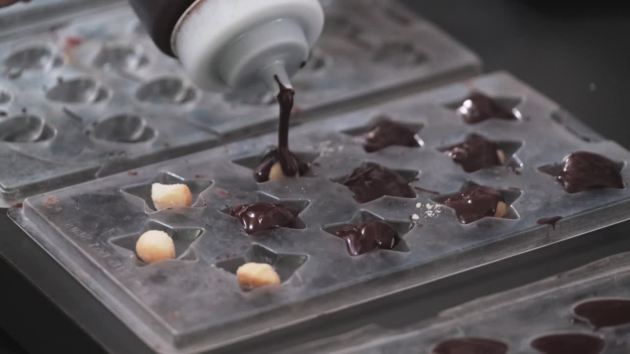 chocolate fresco que se vierte sobre nueces de macadamia en un molde en forma de estrella
