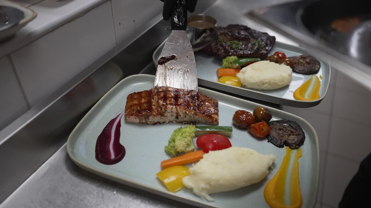 Serveringsporsjon av grillet laks og grønnsaker, kokk med svarte hansker