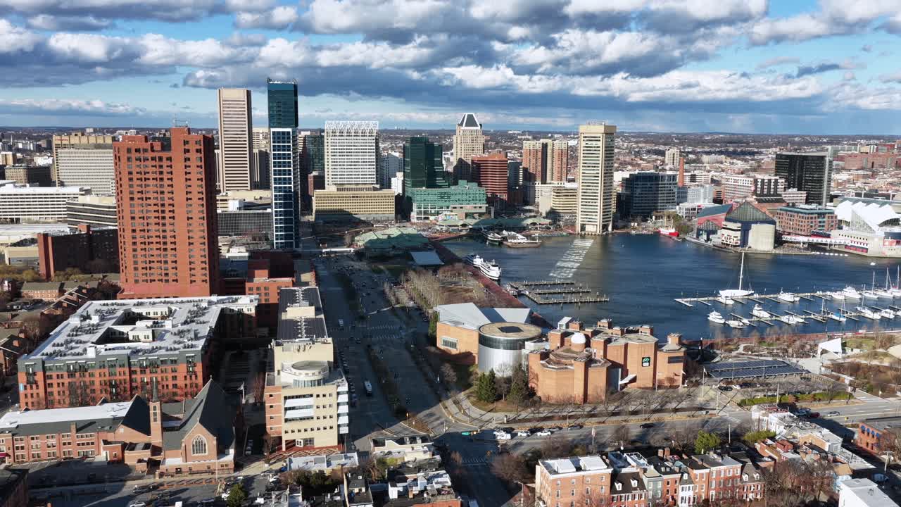 Vista aerea delle case a schiera di Baltimora con l'Inner Harbor e lo skyline del centro sotto la luce del sole, che mostra la storica architettura in mattoni, il lungomare e il paesaggio urbano del Maryland