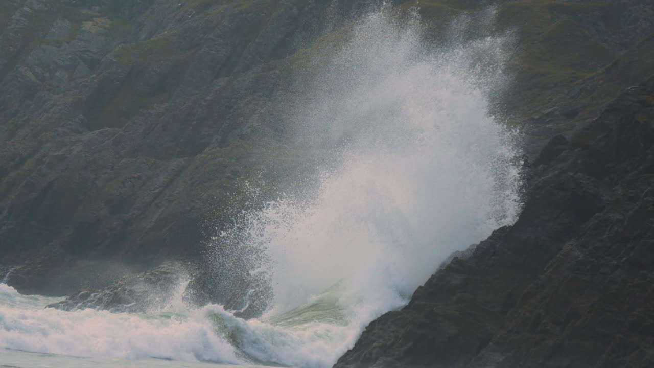 Massive Crashing Waves Slamming into Coastal Rocks on Beach on Gower Coastline in Wales, UK. Cliffs Background as Natural Power of Sea Unleashed. ProRes 4K.