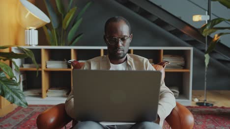 Black Businessman Working on Laptop and Posing at Camera in Office