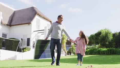 Video-Eines-Glücklichen-Kaukasischen-Großvaters,-Der-Ein-Solarpanel-Trägt-Und-Mit-Seiner-Enkelin-Im-Sonnigen-Garten-Spaziert