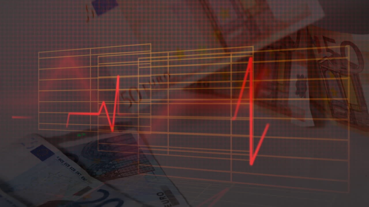 animación de un monitor de latidos cardíacos sobre billetes en euros que caen sobre una mesa.
