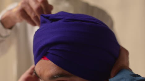 prise de vue rapprochée de deux hommes sikhs utilisant l'aiguille salai lorsqu'ils portent un turban contre un fond plat