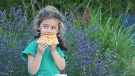 child eating pizza in a garden