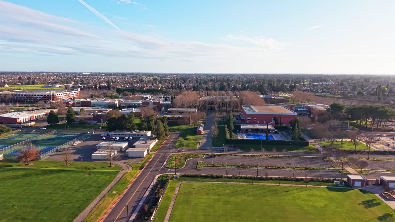 Una ripresa cinematografica con drone inquadra il Cosumnes River College durante l'ora d'oro, dove la luce soffusa, i cortili aperti e le ampie vedute riflettono un'atmosfera serena di un pomeriggio a Sacramento.