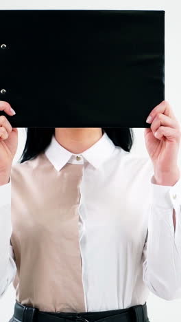 Black folder hides woman face. Attractive secretary opens her face hidden with a folder and smiles isolated on white wall. Businesswoman with positive emotions. Vertical video