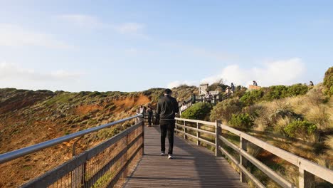 person walking on boardwalk towards scenic cliffs