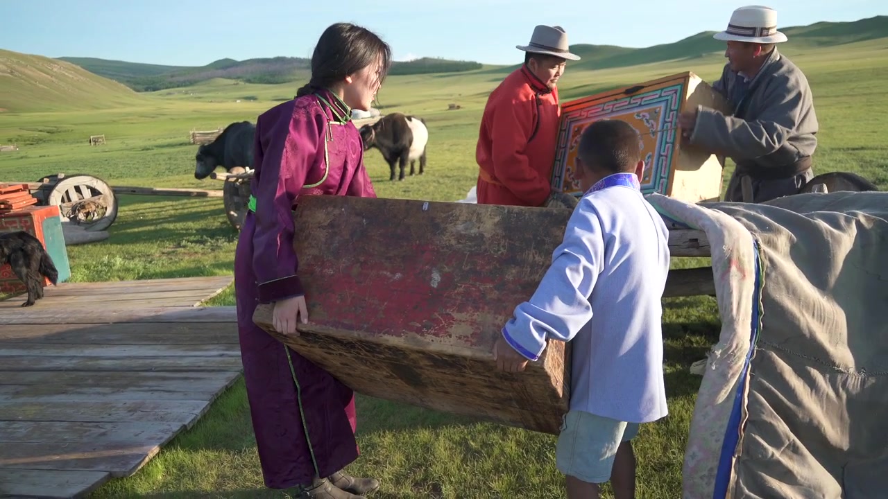 Mongolsk familie læsser traditionel trækiste på vogn på steppen