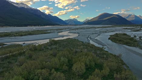 a scenic drone shot of a wide, braided river flowing through a mountain valley