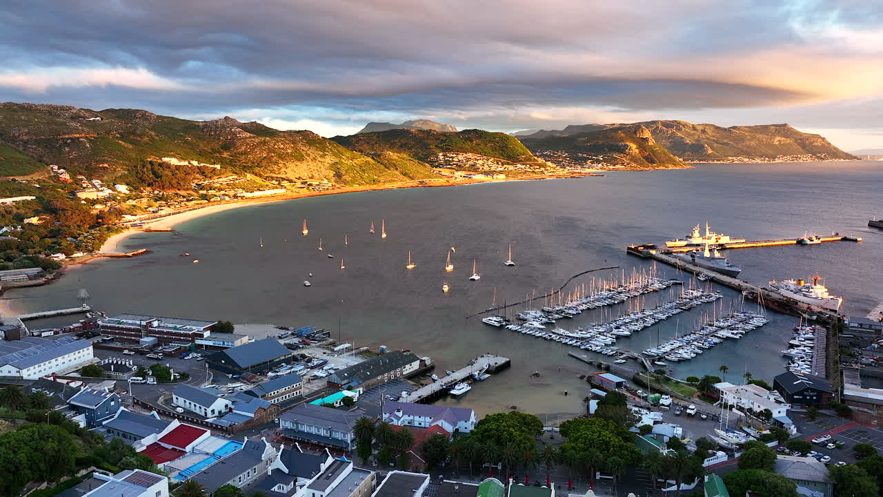 Aerial cinematic drone sunrise Simon's Town naval boat marina fishing small quite city Cape Town South Africa early sunlight clouds Table Mountain Fish Hook Muizenberg penguins backward movement