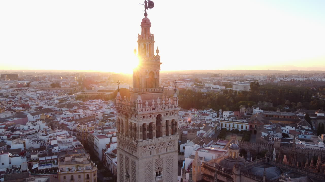 Carrellata aerea all'indietro che rivela la torre della Giralda nella famosa cattedrale europea di Siviglia, con suggestiva luce solare sullo sfondo.
