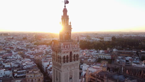 aerial dolly out revealing giralda tower in the famous european cathedral of seville with scenic sunlight behind