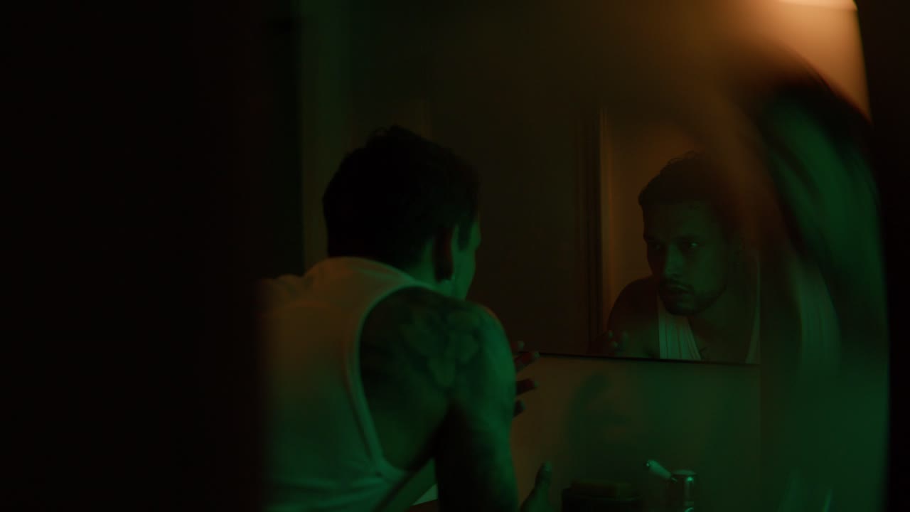 Man looking in the mirror in a dimly lit bathroom