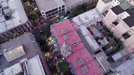 Aerial-view-flying-over-colourful-red-rooftop-commercial-business-bell-tower-in-Santiago-urban-city-centre,-Chile