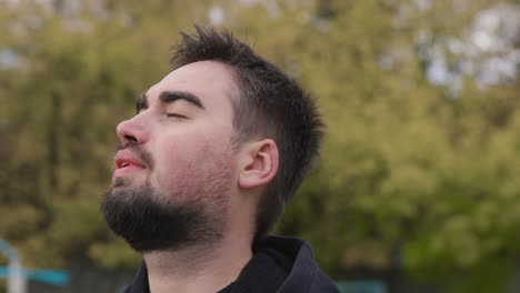 hombre relajado respirando aire fresco de pie en el parque por la mañana