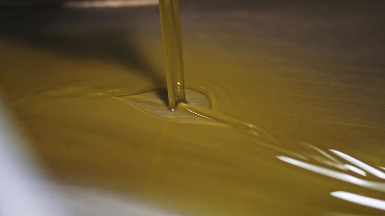 Vista ravvicinata dell'olio d'oliva dorato che scorre durante il processo di estrazione