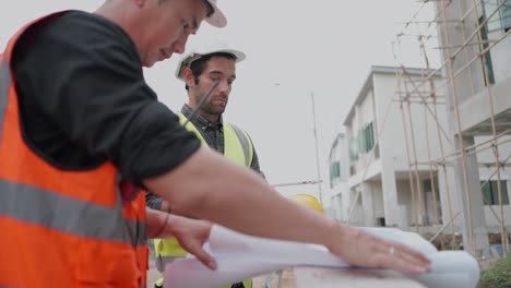 professional civil engineer or building architect discussing with foreman about house model in blueprint in housing project construction site. team of contractor in safety uniform working in real estate business.