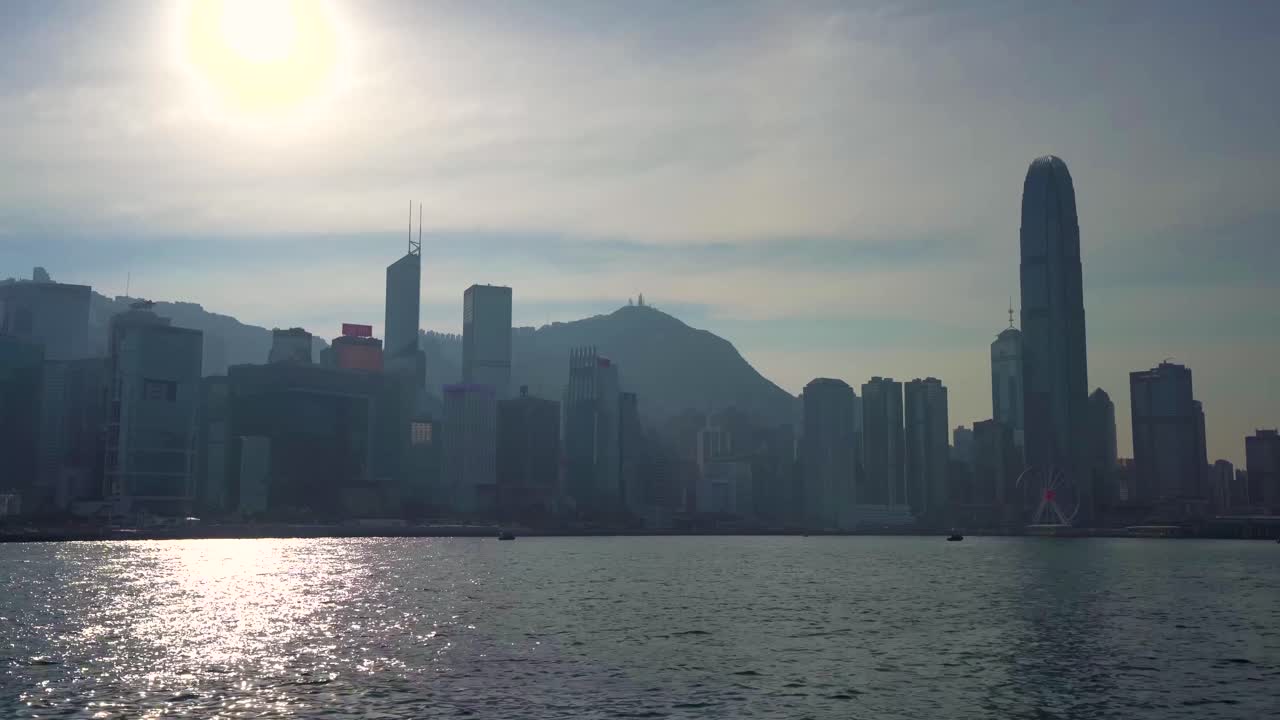 hermosa y famosa silueta del horizonte de la mega ciudad de hong kong, navegando a través del puerto marítimo de victoria en un barco en un día de verano soleado y caluroso, sol brillante que se refleja en el agua