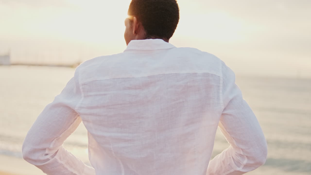 Uomo che fa stretching e si gode l'ora d'oro su una spiaggia serena