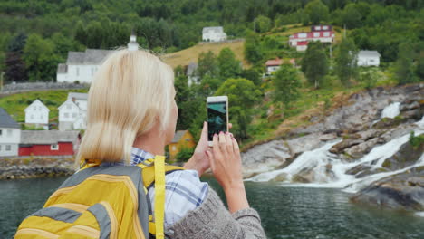 traveler photographs a picturesque landscape in norway a waterfall and traditional norwegian houses