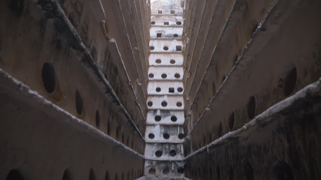 Slow tilt down of an old dovecote with pigeons in Barbate, Spain,