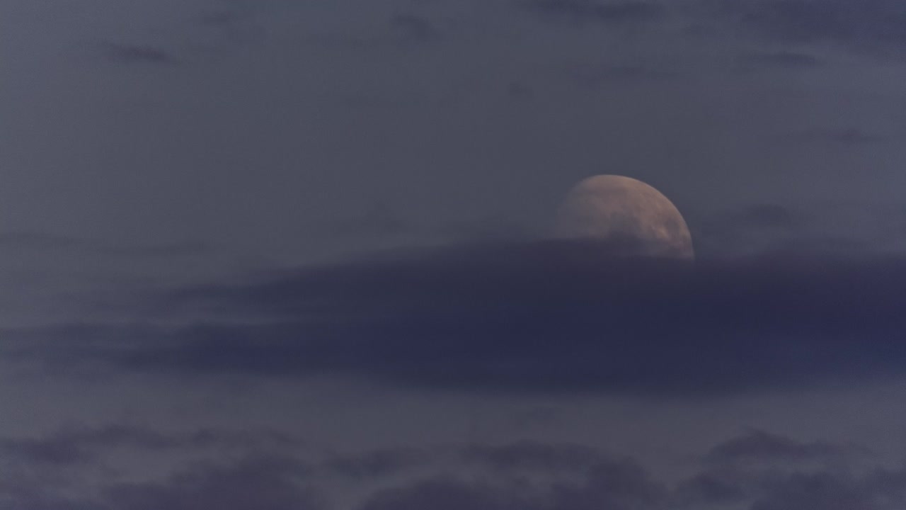 Daylight Moon. The descending Moon among light clouds in daylight at 2am arctic summer. Time Lapse