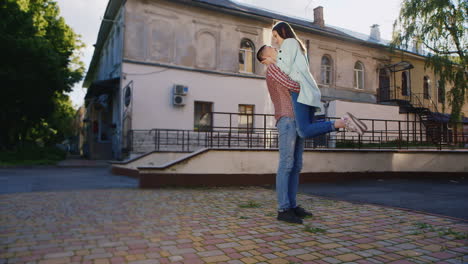 young couple hugging on the street the guy holding the girl in his arms they kiss  hd video