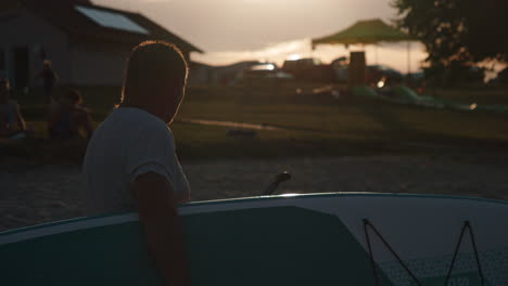 silhouette of man holding paddleboard against sun during sunset, beautiful cinematic closeup