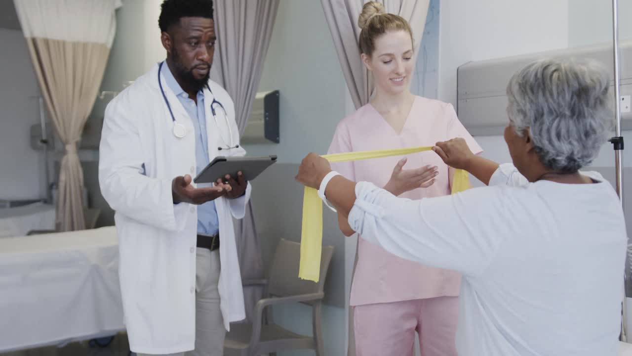 Diverse male doctor talking with happy female physiotherapist and senior female patient, slow motion