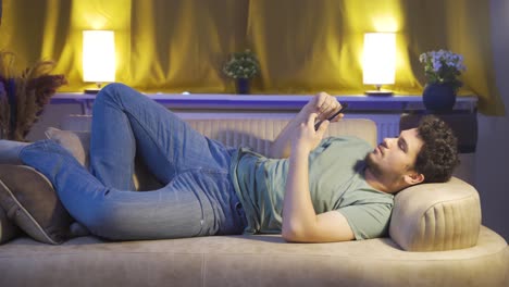 homem a adormecer à noite com o telemóvel na mão.
