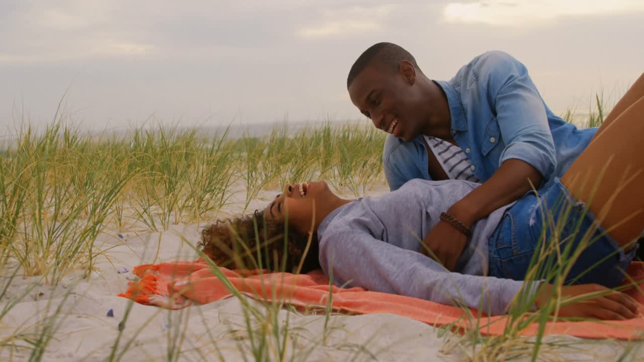 vista lateral de una pareja afroamericana divirtiéndose en la playa 4k