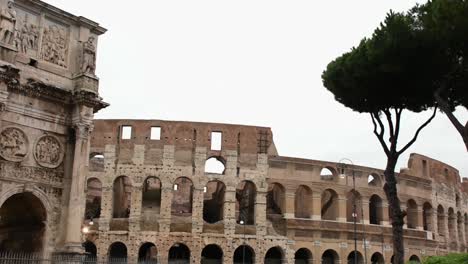 Arch-of-Constantine-and-the-Colosseum,-ancient-city-landmarks,-panning,-view-in-a-rainy-day,-Rome,-Italy