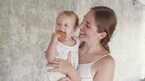 mom holding toddler eating cookie