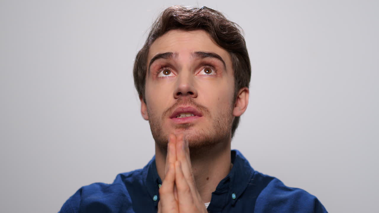 Hombre guapo rezando en estudio. Retrato de hombre concentrado haciendo una oración.