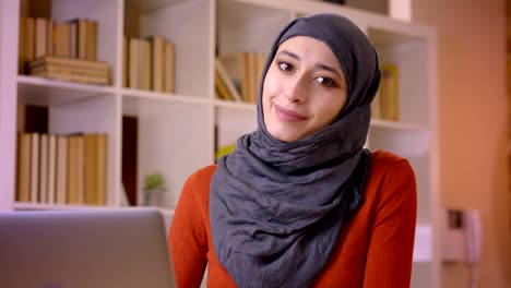 closeup shoot of young attractive muslim female employee typing on the laptop being successful and happily smiling indoors in the office