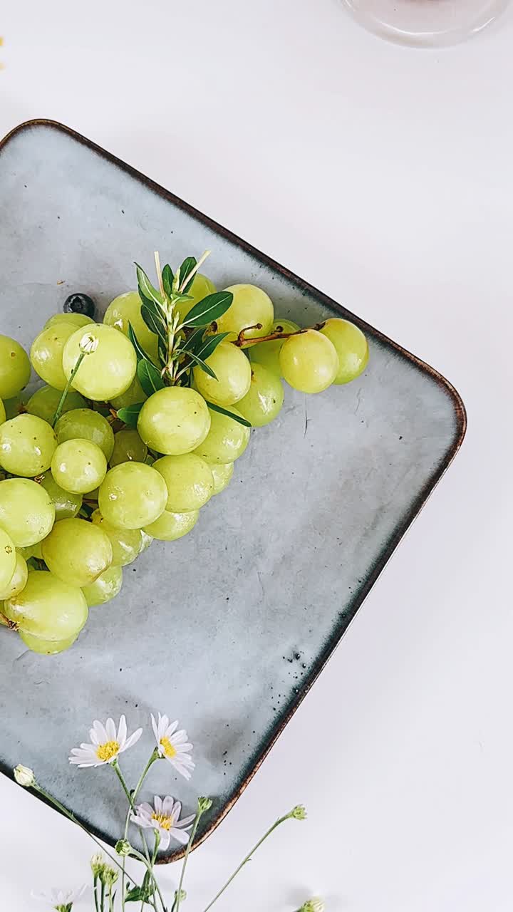 uvas verdes en un plato gris con flores