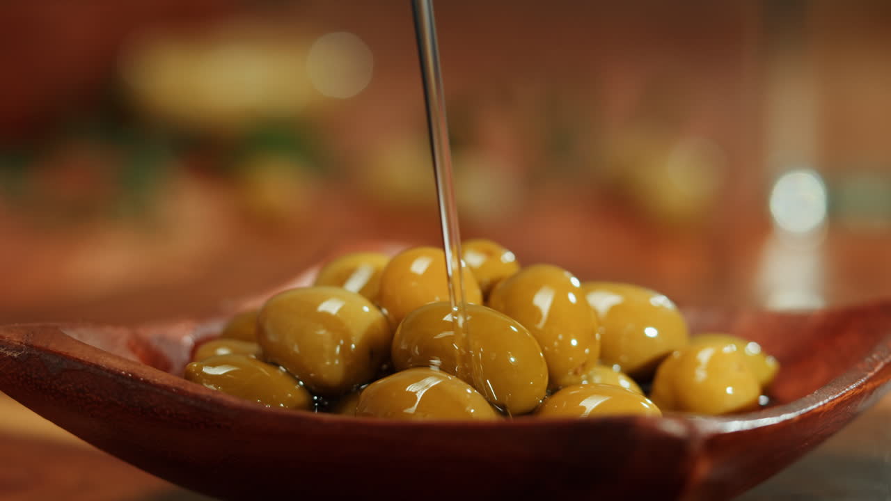 Pouring Olive Oil Over Green Olives
