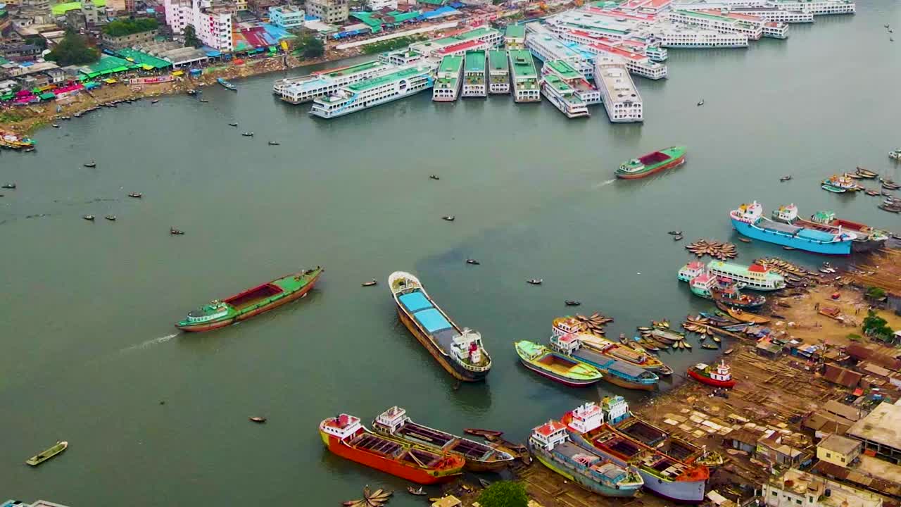 Voo de drone aéreo sobre o Rio Buriganga, porto de navios de carga coloridos, e paisagem urbana tradicional de Bangladesh com sua atmosfera vibrante