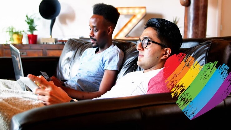 Animation of rainbow heart over gay couple using electronic devices