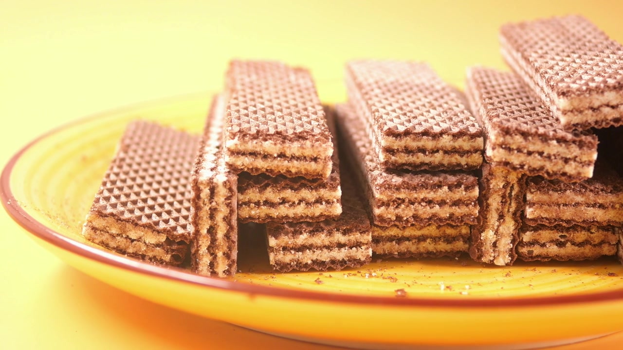 Deliziosi biscotti wafer al cioccolato su un piatto giallo