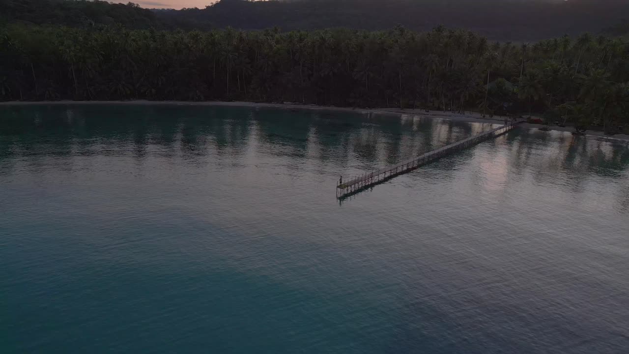 Pescatore solitario su un lungo molo al mattino.