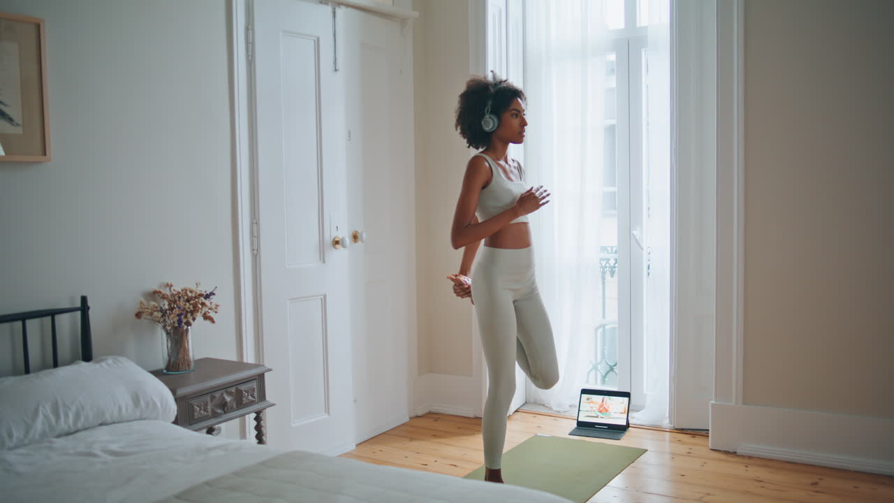 chica tranquila estirando las piernas alfombra modelo africano calentando el cuerpo practicando yoga