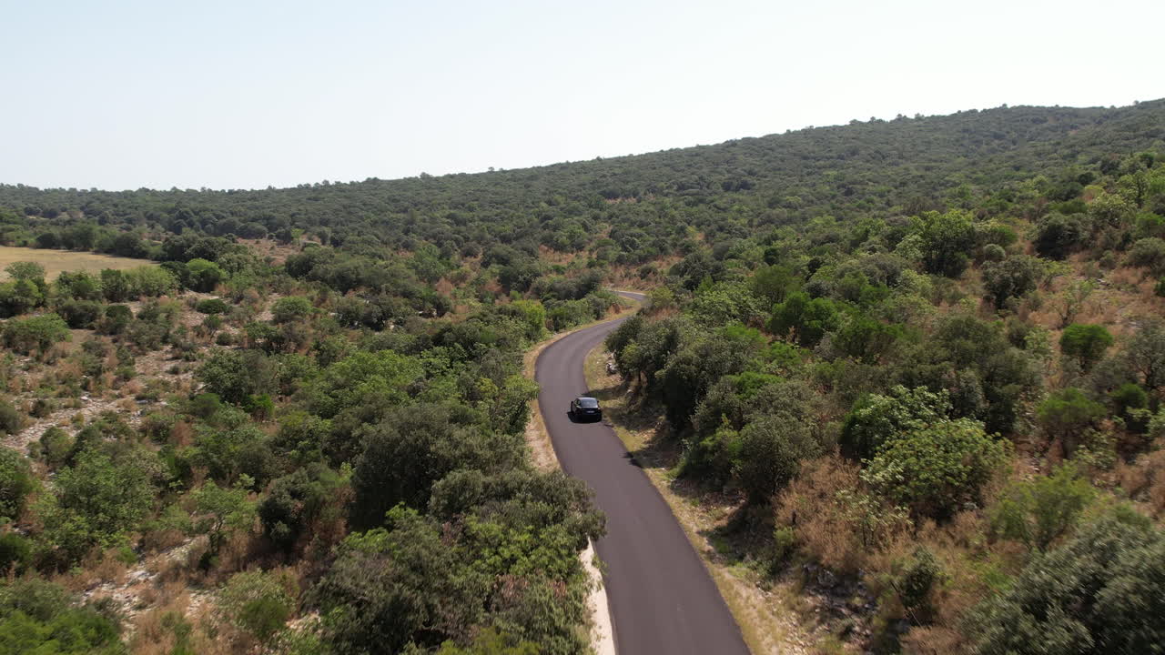 coche eléctrico negro conduciendo en una ronda a través de la vegetación francia día soleado aérea