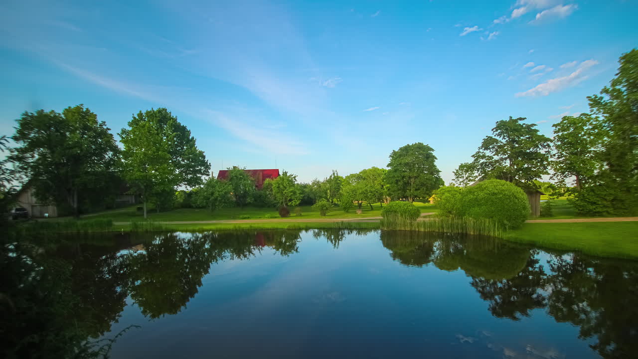 나무 로  ⁇ 인 시골 오두막 에서 호수 위 에 몇 개 의 구름 이 있는  ⁇ 은 파란 하늘 의 타임  ⁇ 스 는 물 에 반사 되는 것 을 보여준다