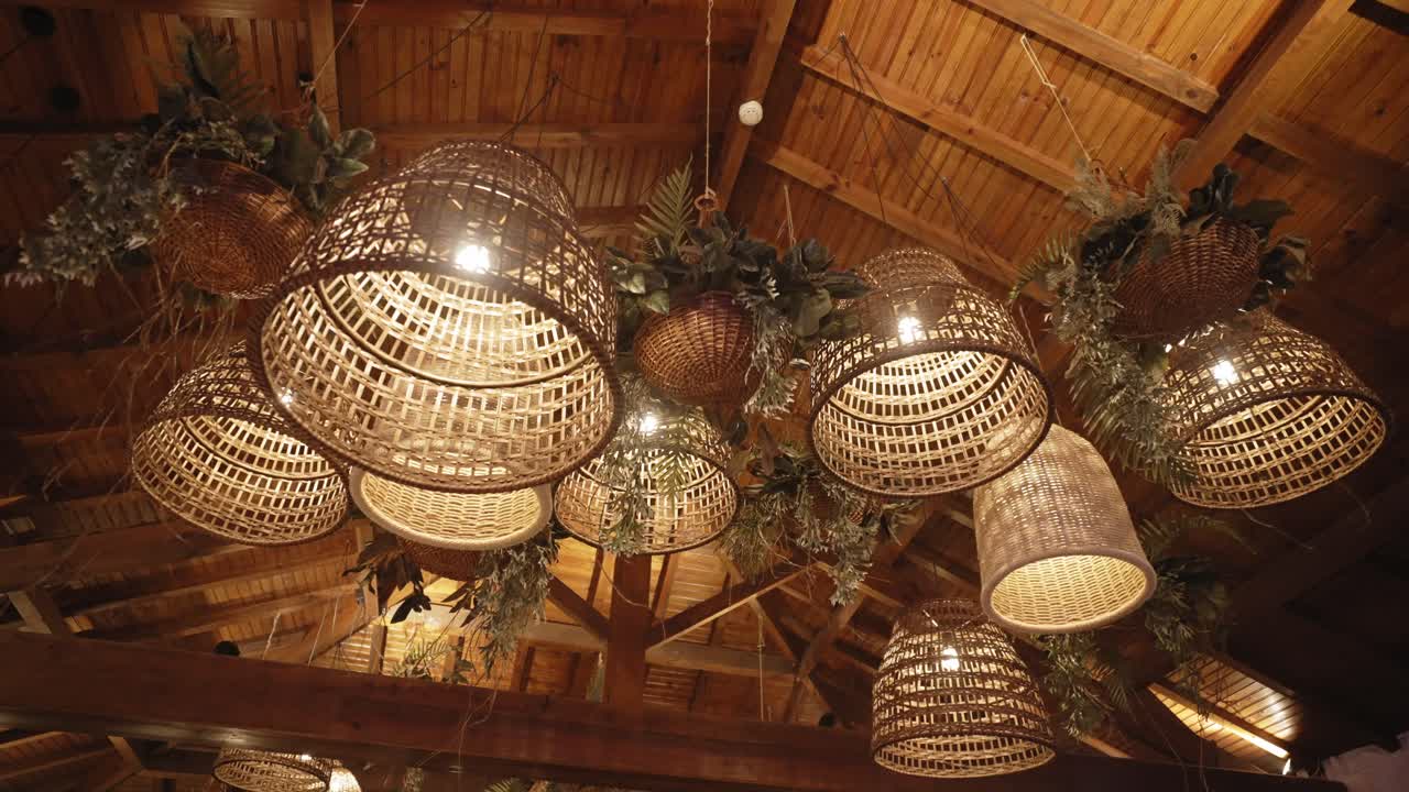 Wicker lanterns and greenery hang from wooden ceiling in rustic evening event decor