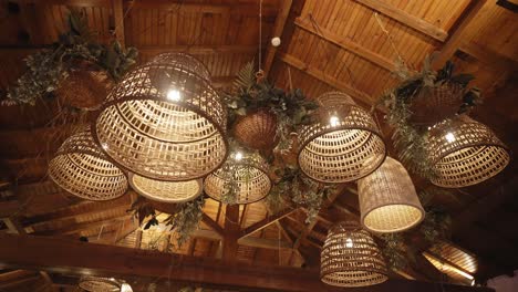 wicker lanterns and greenery hang from wooden ceiling in rustic evening event decor